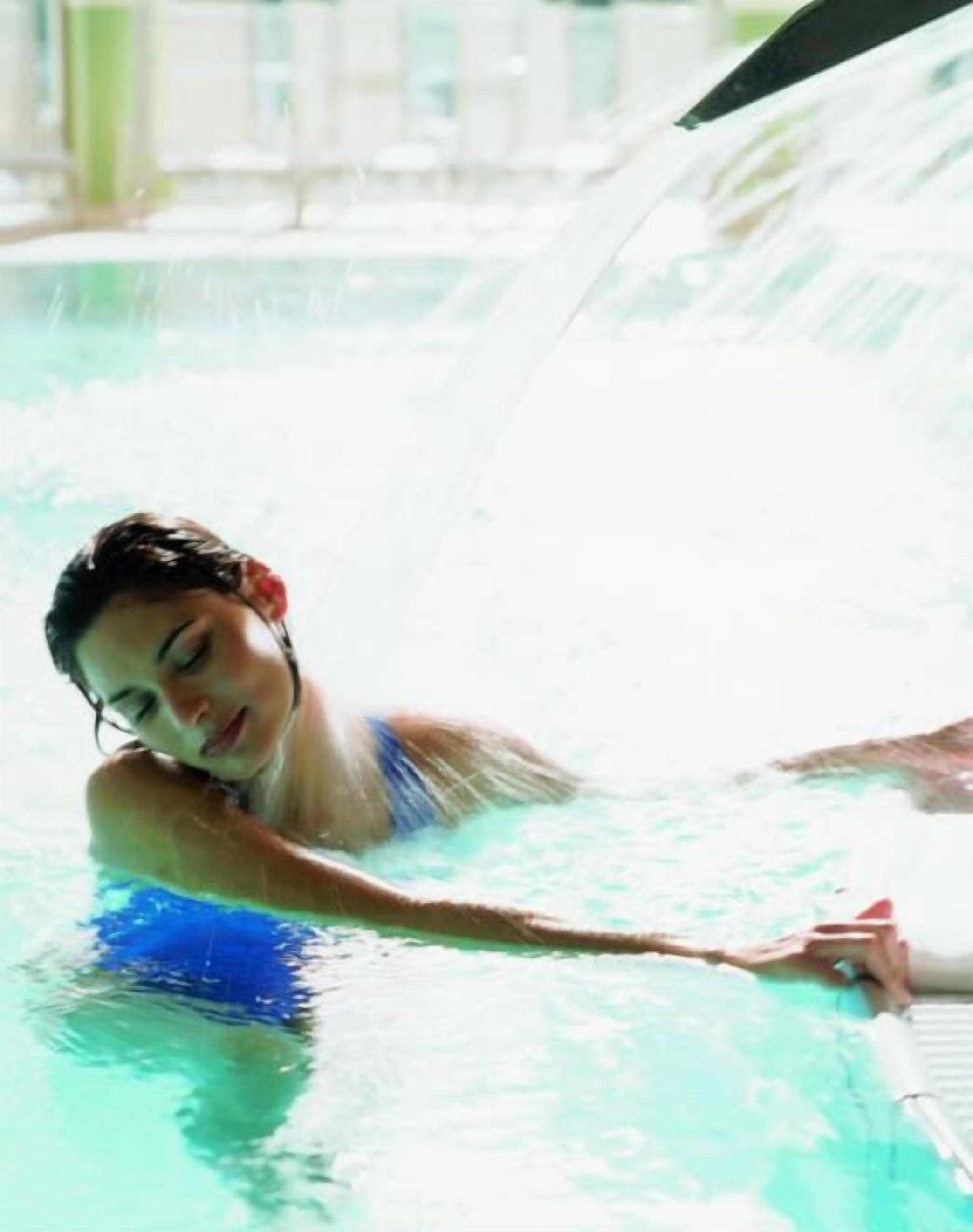 A person in a swimming pool with a water slide.