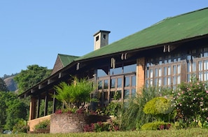 Eine Lodge mit großer Veranda, Schornstein und einem Garten mit verschiedenen Pflanzen und Blumen.