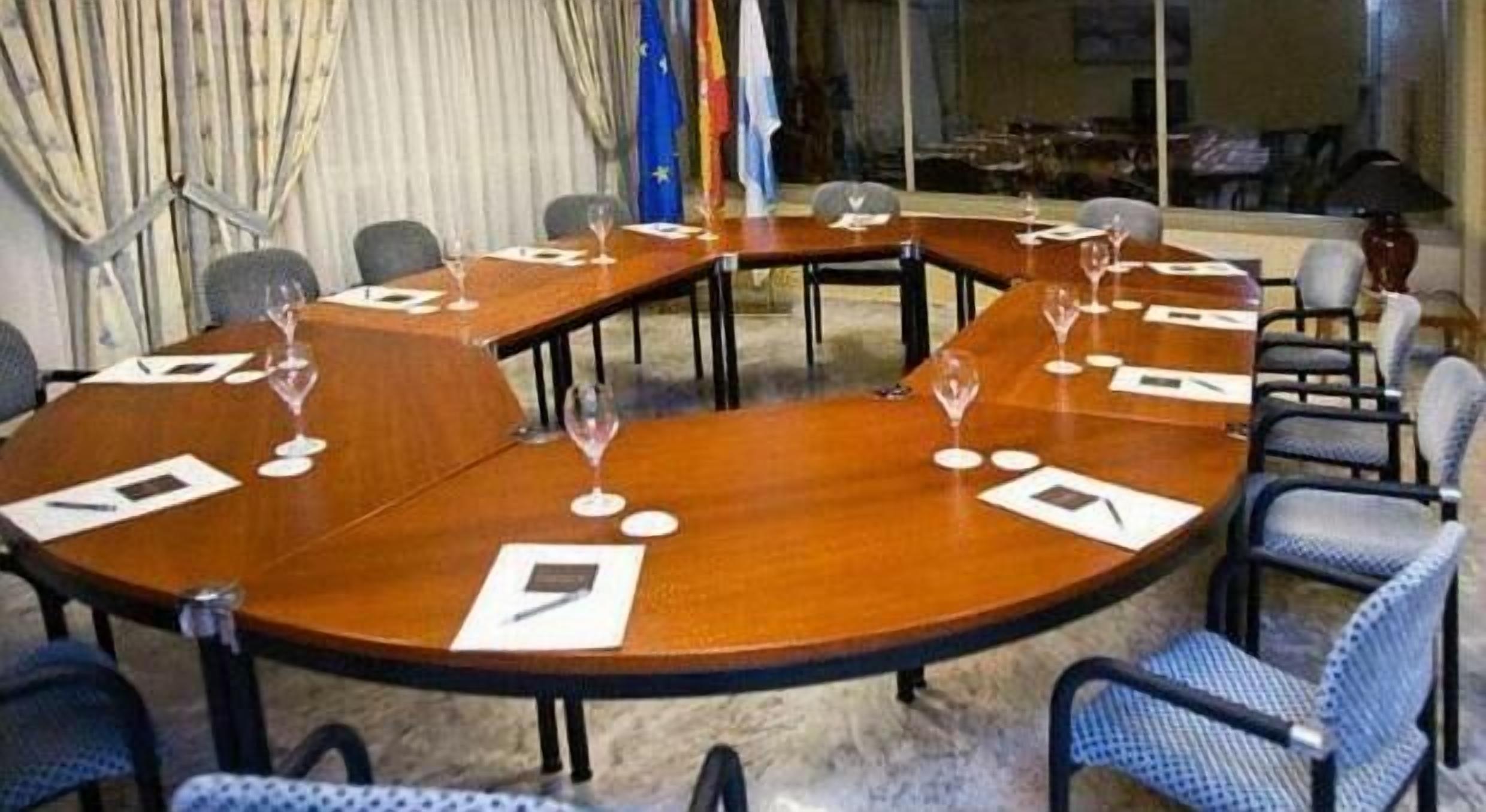 A conference room with a large oval table, chairs, and flags.