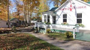 A white building with a green roof and a sign reading "Birch Cliff Lodge." - Birch Cliff Lodge on Baptiste Lake (Hastings Highlands)
