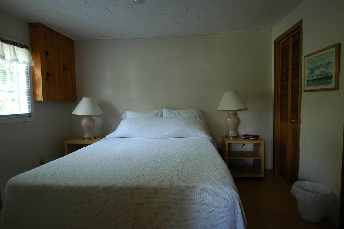 A neatly made bed with two bedside tables, each with a lamp and a small shelf.