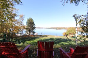 A lakeside view with red Adirondack chairs, a playground, and a dock with boats.