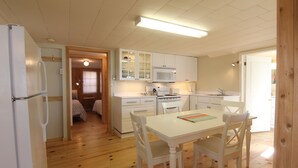 A compact kitchen with white cabinets, a microwave, and a dining table with chairs. - Birch Cliff Lodge on Baptiste Lake (Hastings Highlands)
