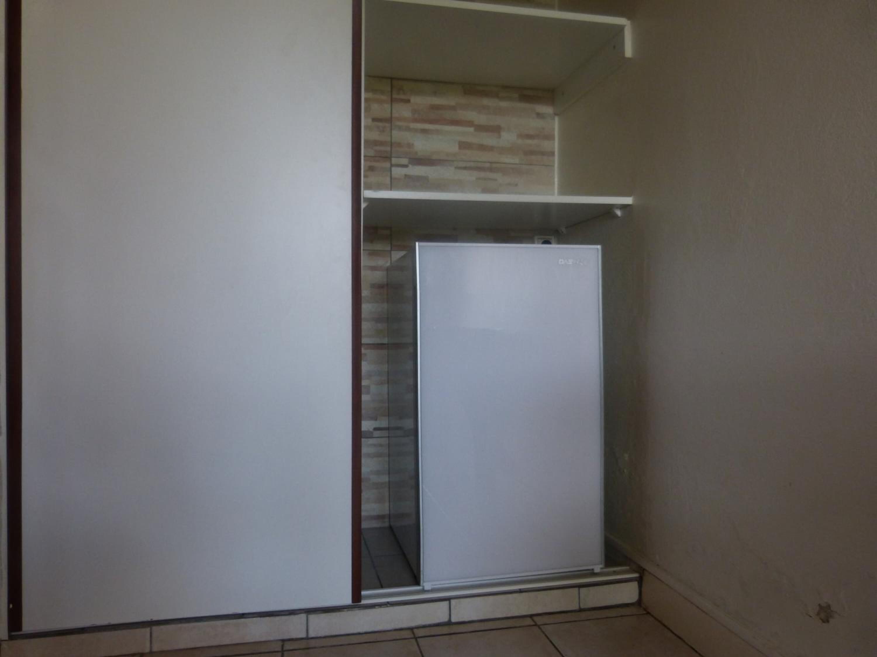 Una habitación pequeña y cerrada con un armario blanco y un refrigerador.