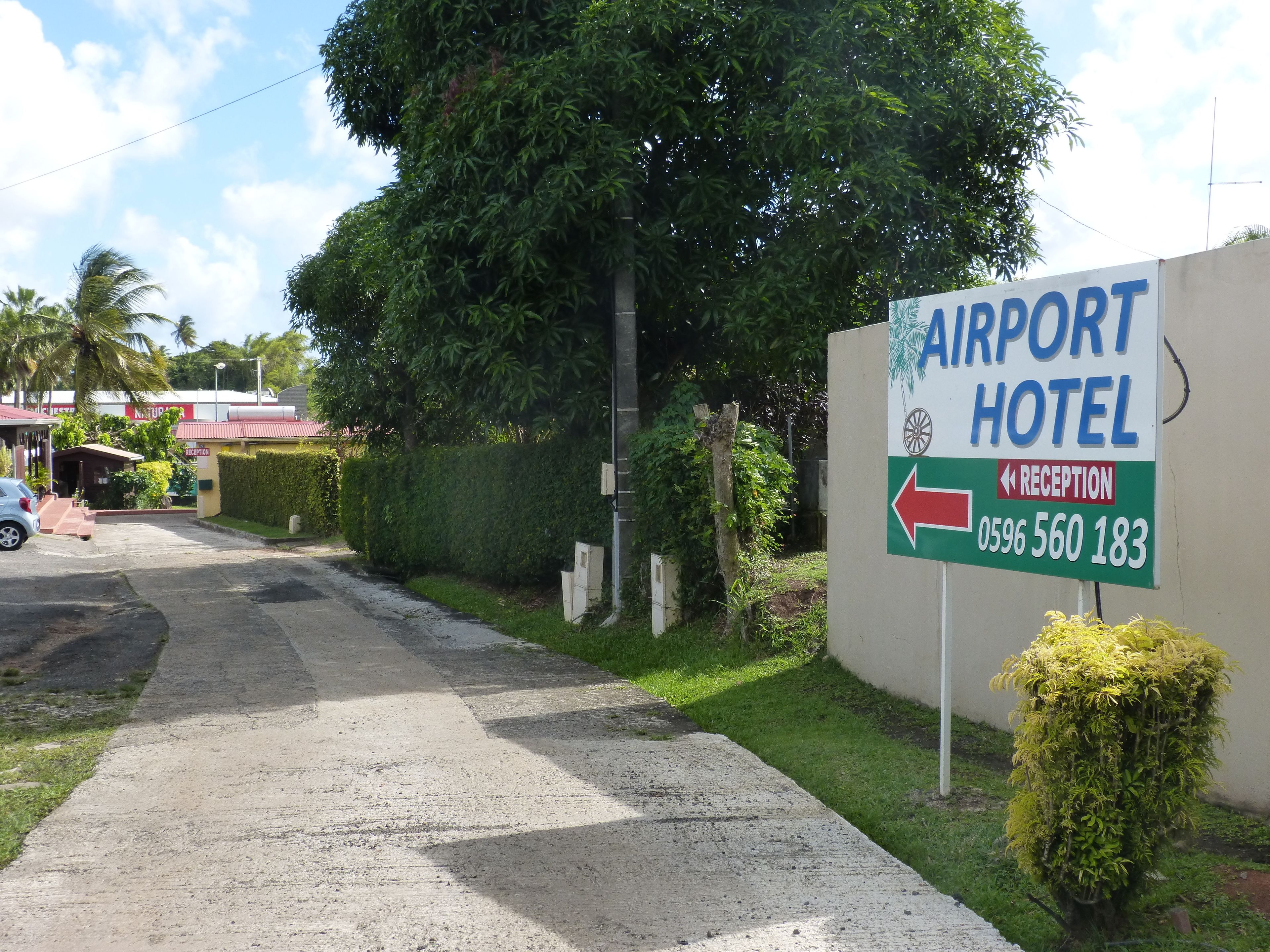 Une enseigne indiquant l’hôtel de l’aéroport, avec une flèche indiquant la direction de la réception et le numéro de téléphone.