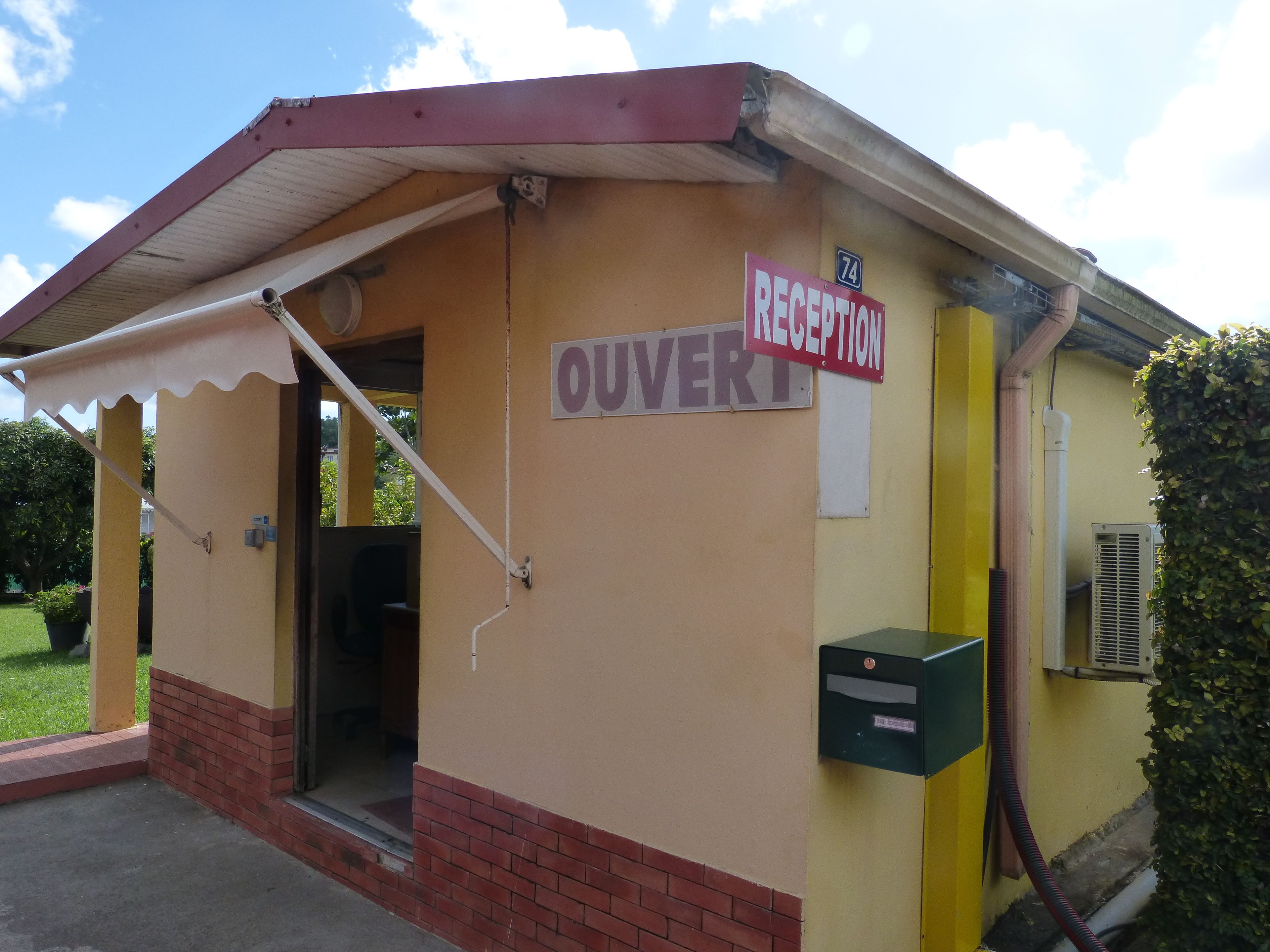 A building with a reception area, a sign indicating 'OUVERT', and a mailbox.