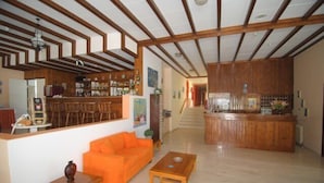 Un vaste espace de vie doté d’un plafond en bois, d’une cuisine avec un bar et d’un canapé orange.