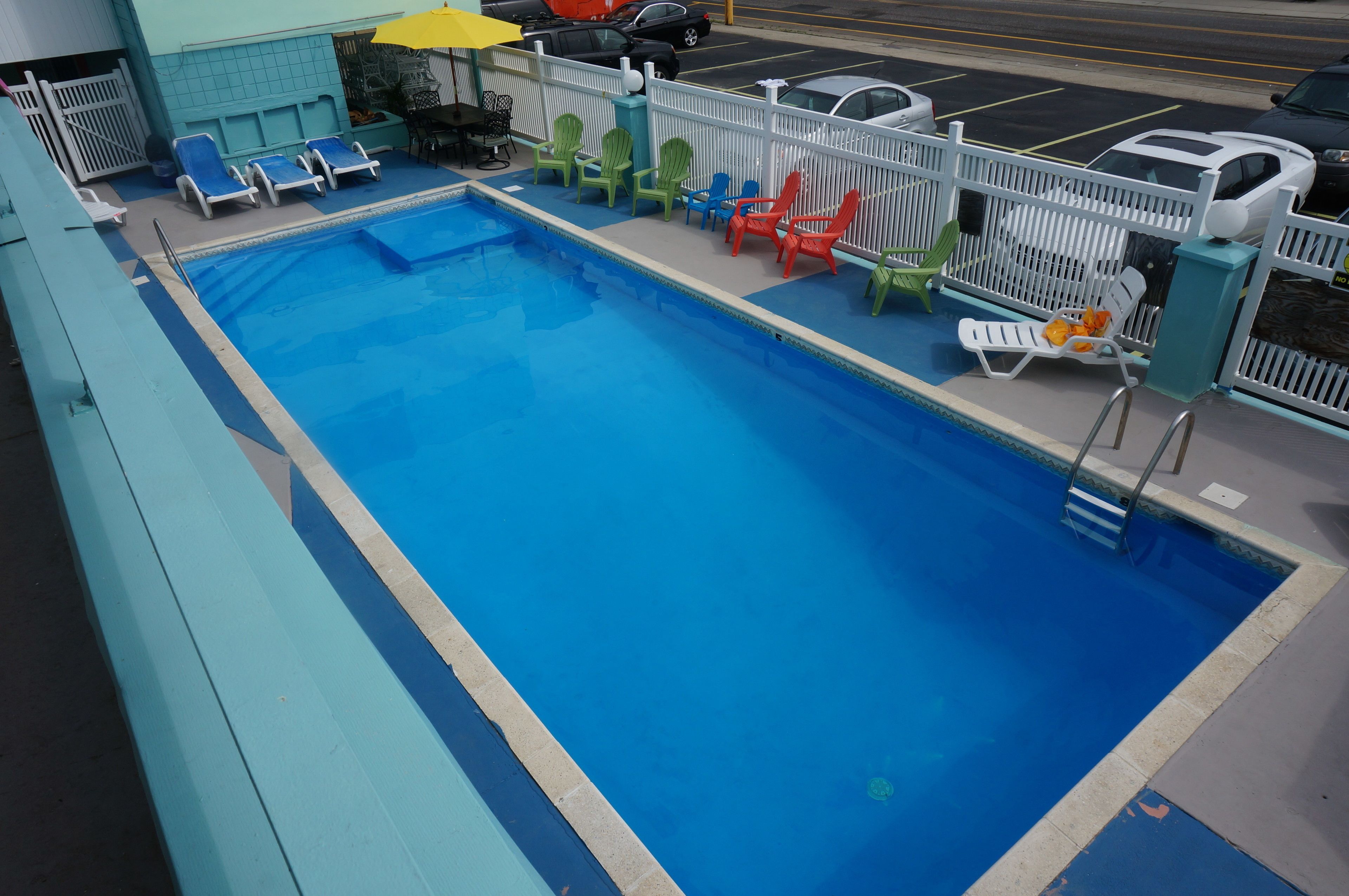 A swimming pool with lounge chairs and a fence.