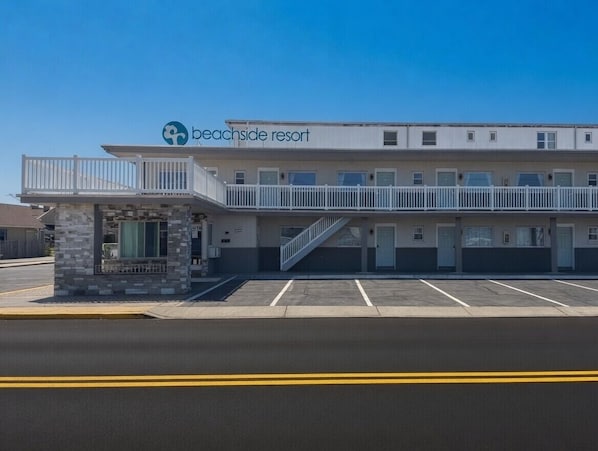 A beachside resort with a covered walkway, a stone structure, and a parking lot.