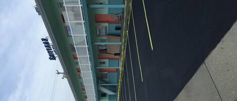 A multi-story hotel with balconies, a parking area, and a clear sky.