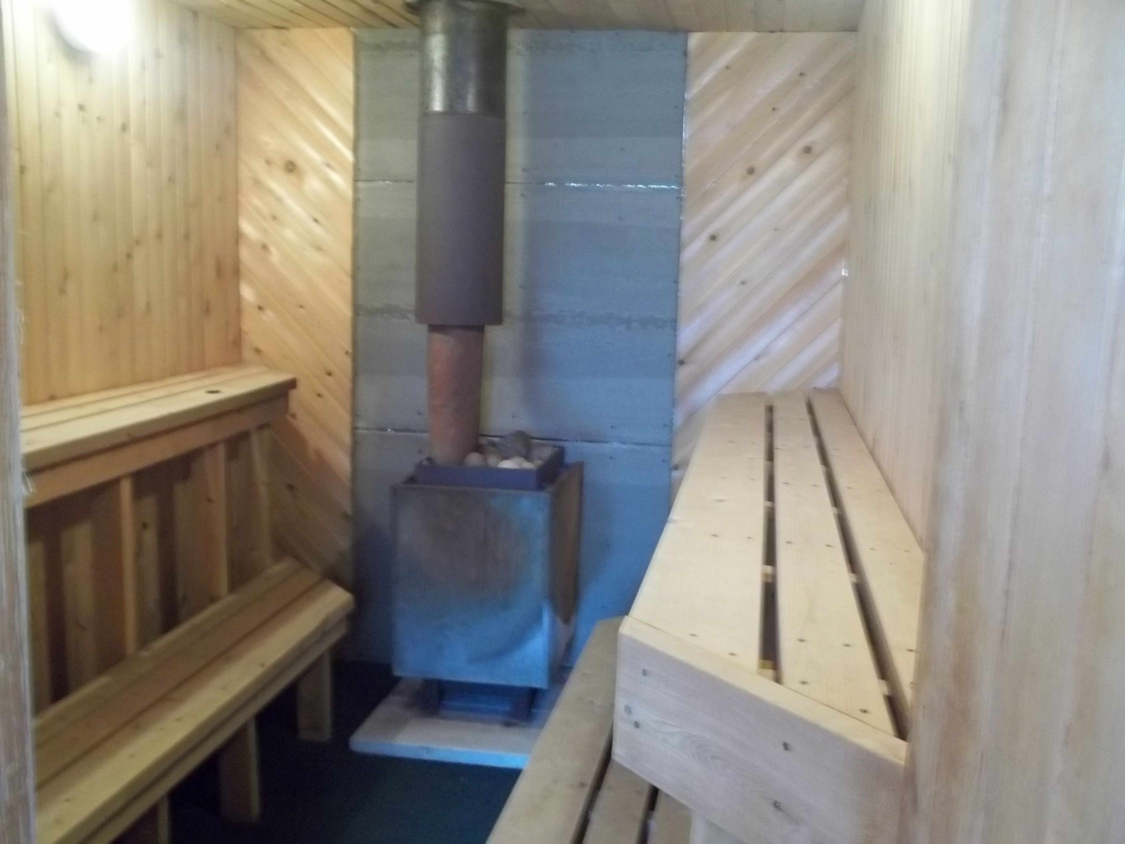 A sauna with a wooden bench and a metal heater.