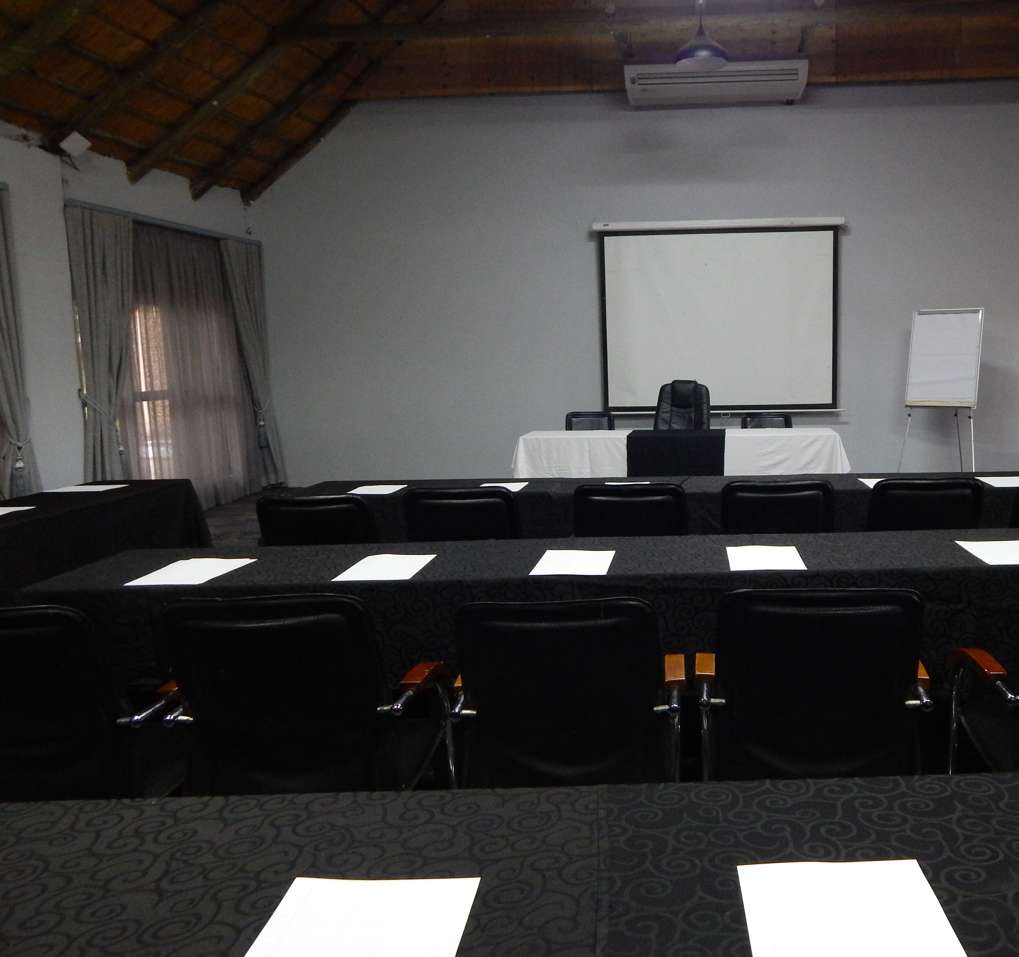 A conference room with a long table, chairs, a projector screen, and a whiteboard.