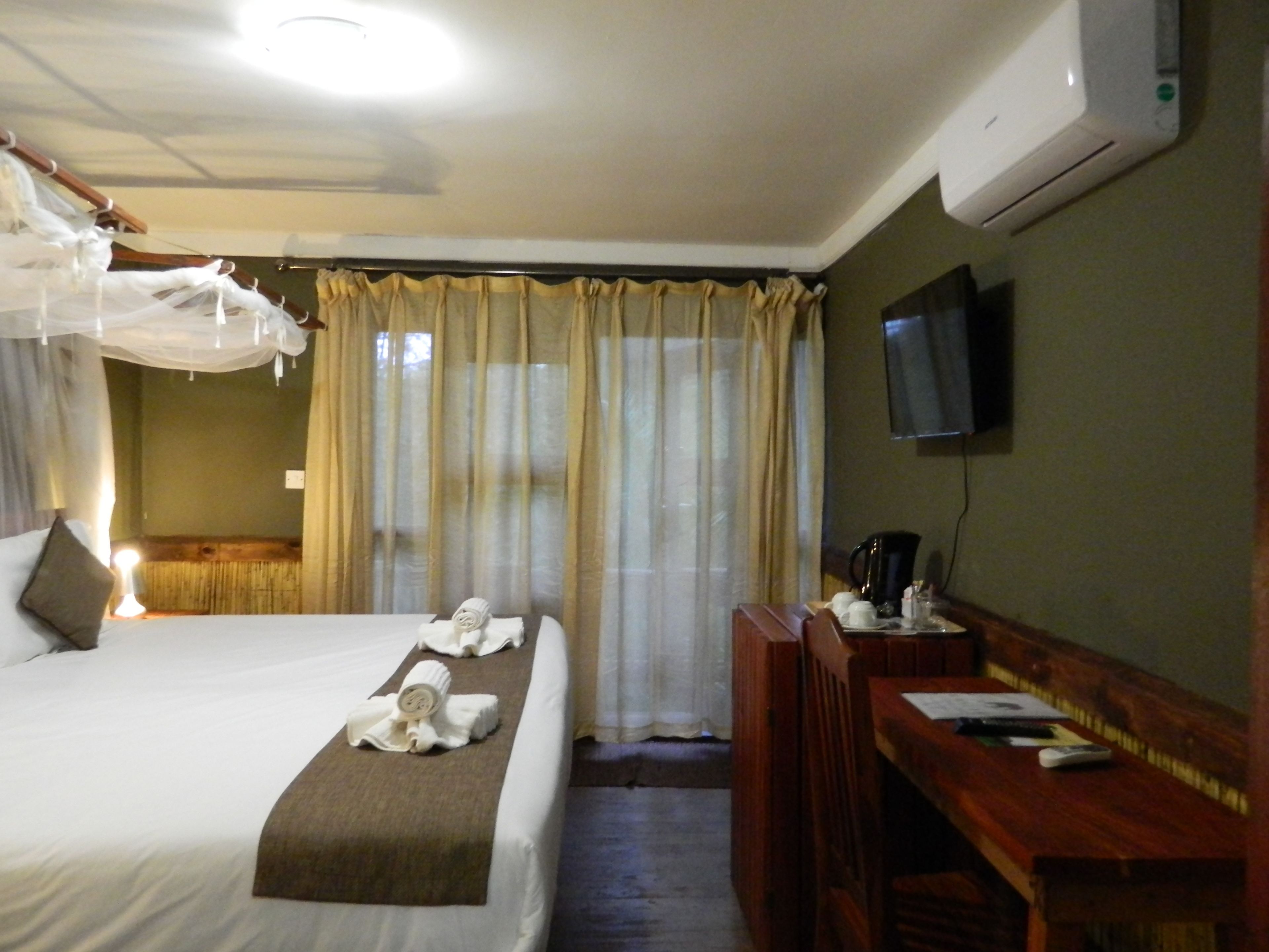 A hotel room with a bed, a desk, a television, and curtains.