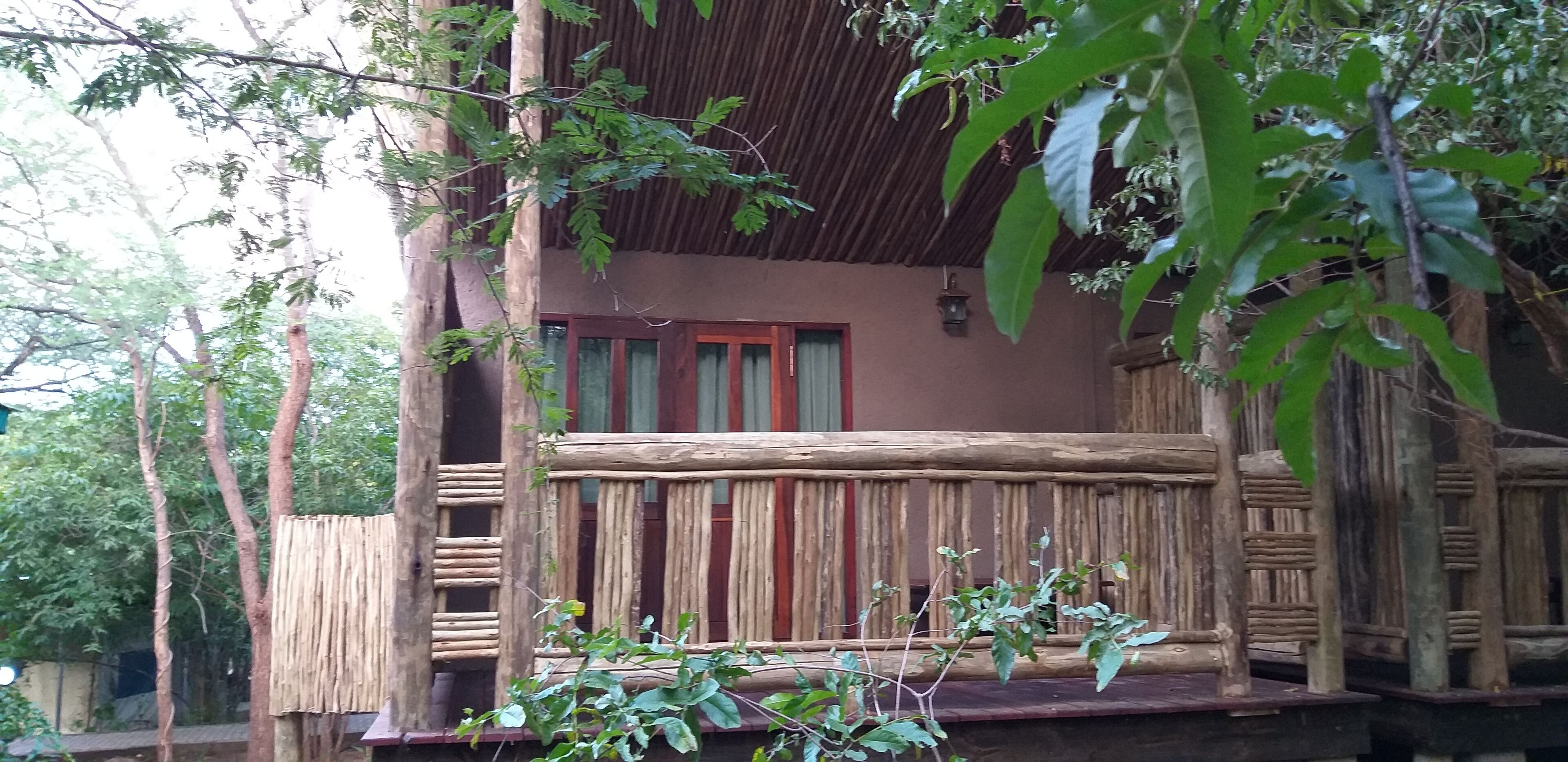 Una cabaña de madera con balcón, rodeada de árboles.