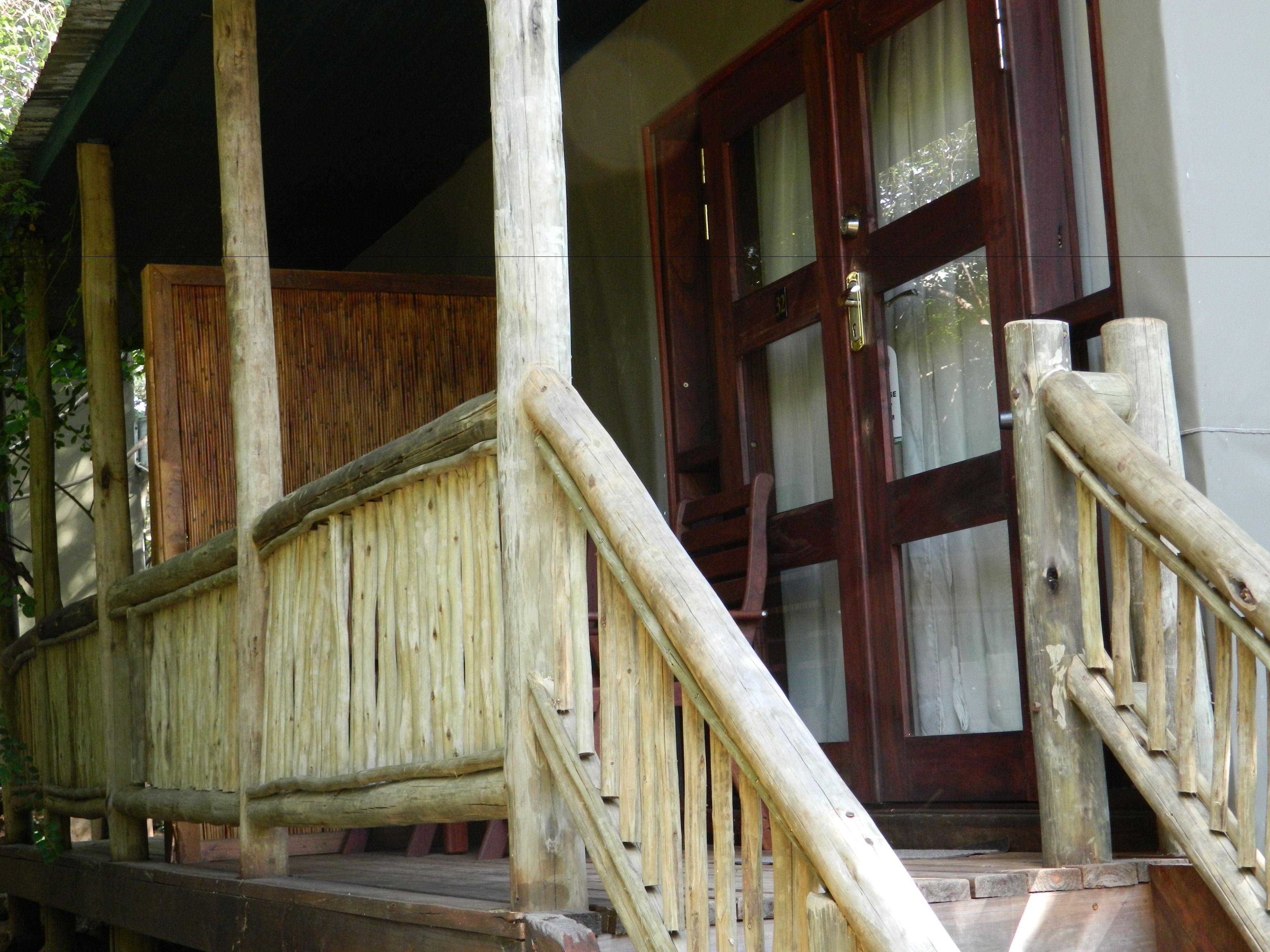 Un portico in legno con ringhiera e porta in legno con vetri.