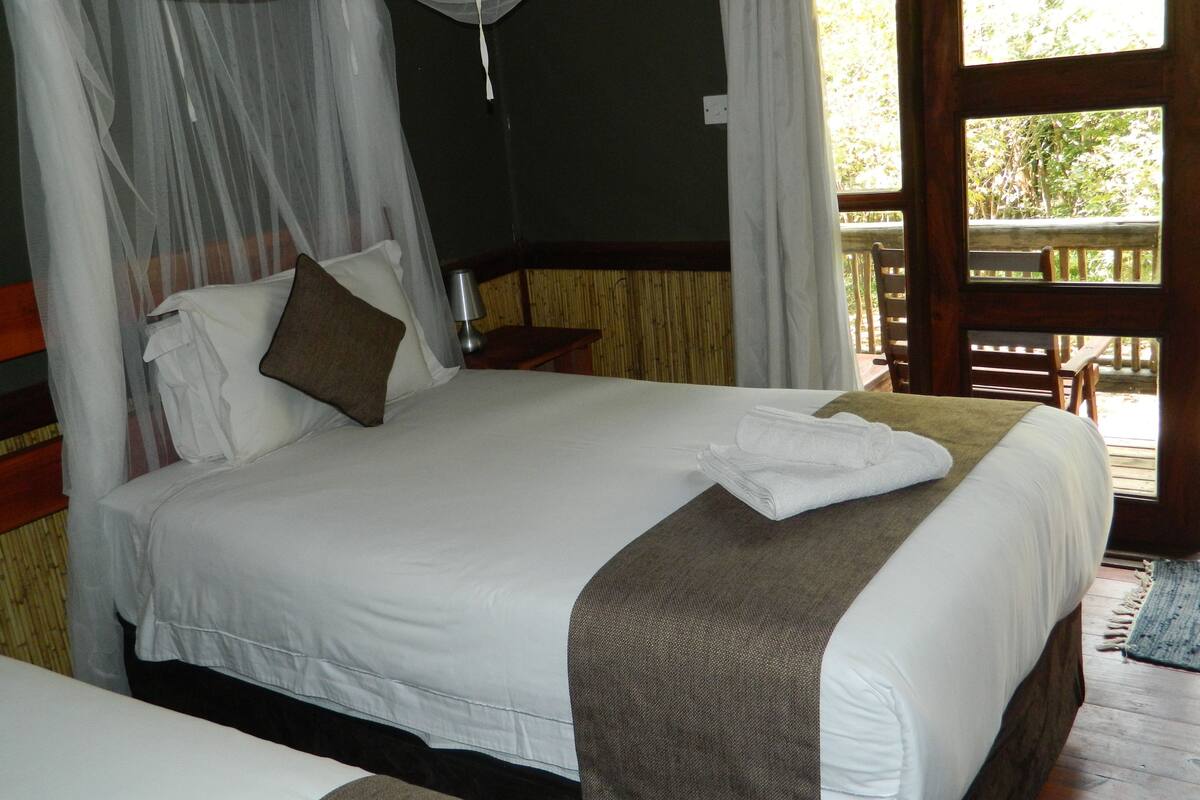 A bed with white linens, a brown pillow, and a canopy.