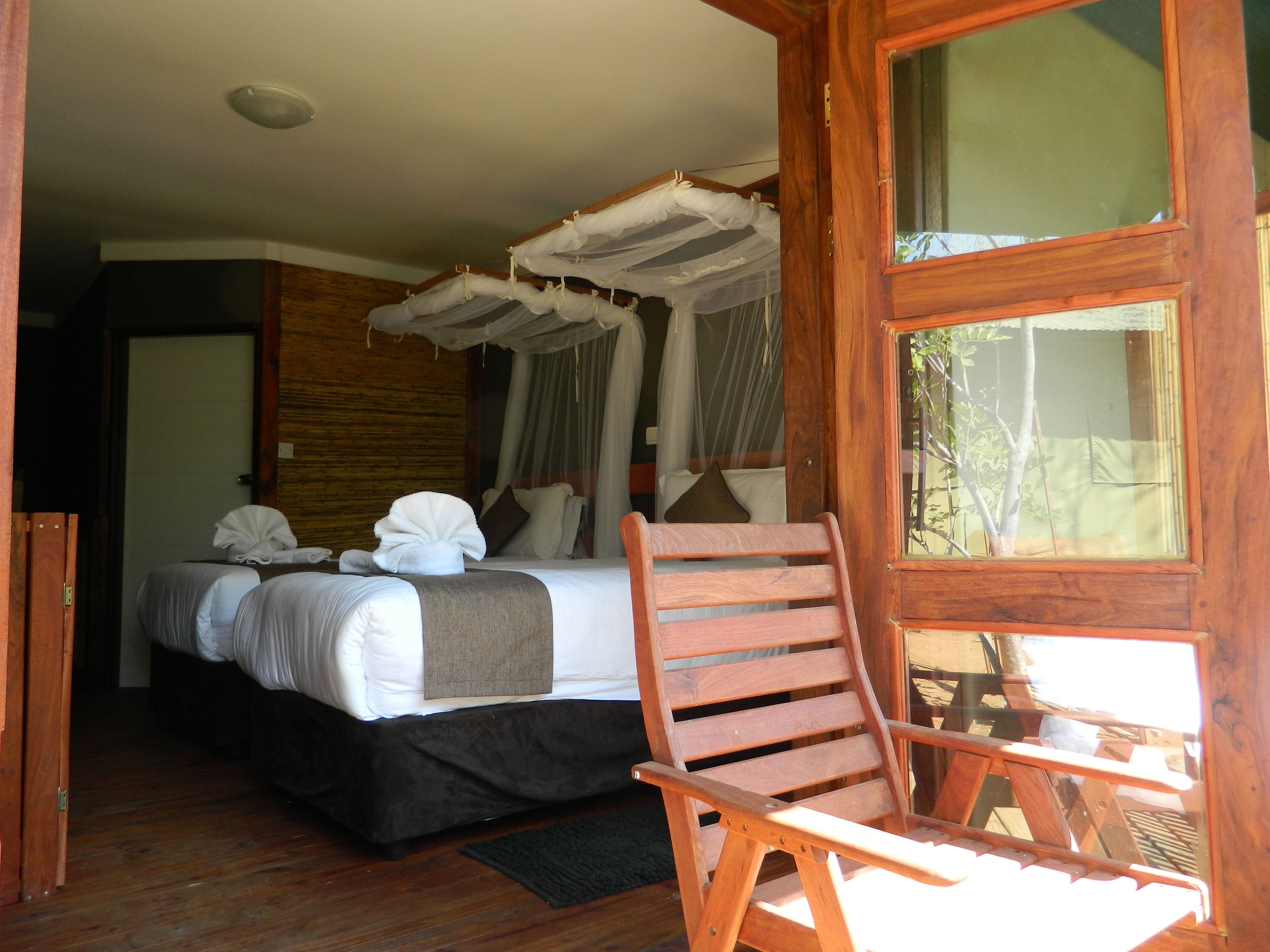A bedroom with a bed, a wooden chair, and a window.