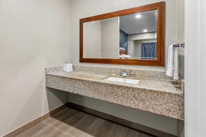 A bathroom with a granite countertop, a sink, a mirror with a wooden frame, and a towel rack.