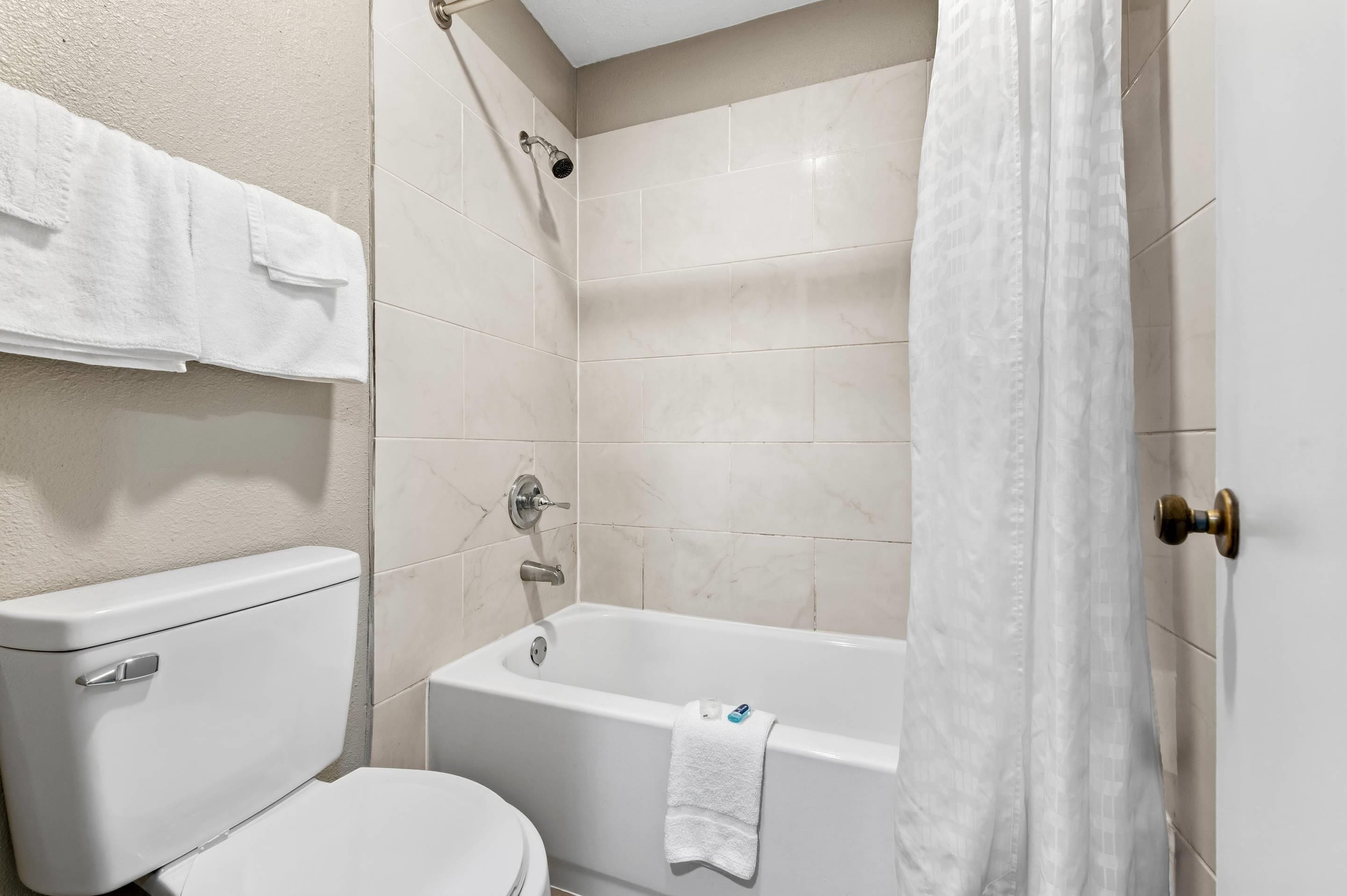 A bathroom with a toilet, bathtub, and shower curtain.