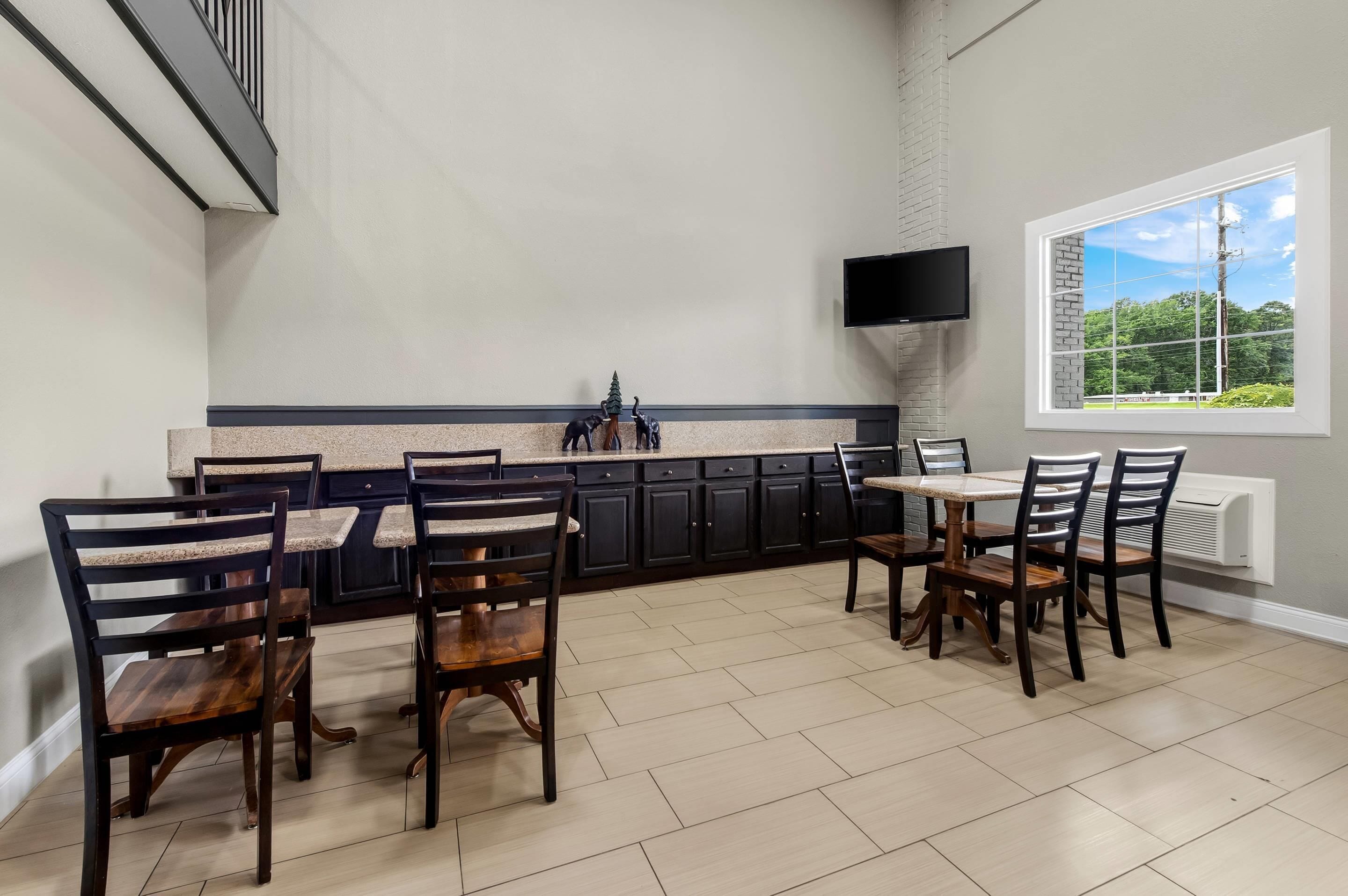 A spacious kitchen with dark cabinets, a granite countertop, and a dining area with wooden chairs.