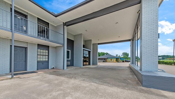 A building with a covered entrance, a garage, and a balcony.