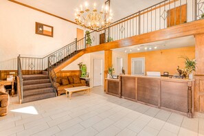 Un hall d’entrée spacieux avec un escalier, un comptoir d’accueil et un lustre.