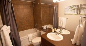 Un baño con bañera, inodoro y dos lavamanos.