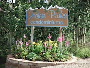 Letrero de condominios Indian Peaks rodeado por un jardín con diversas flores.