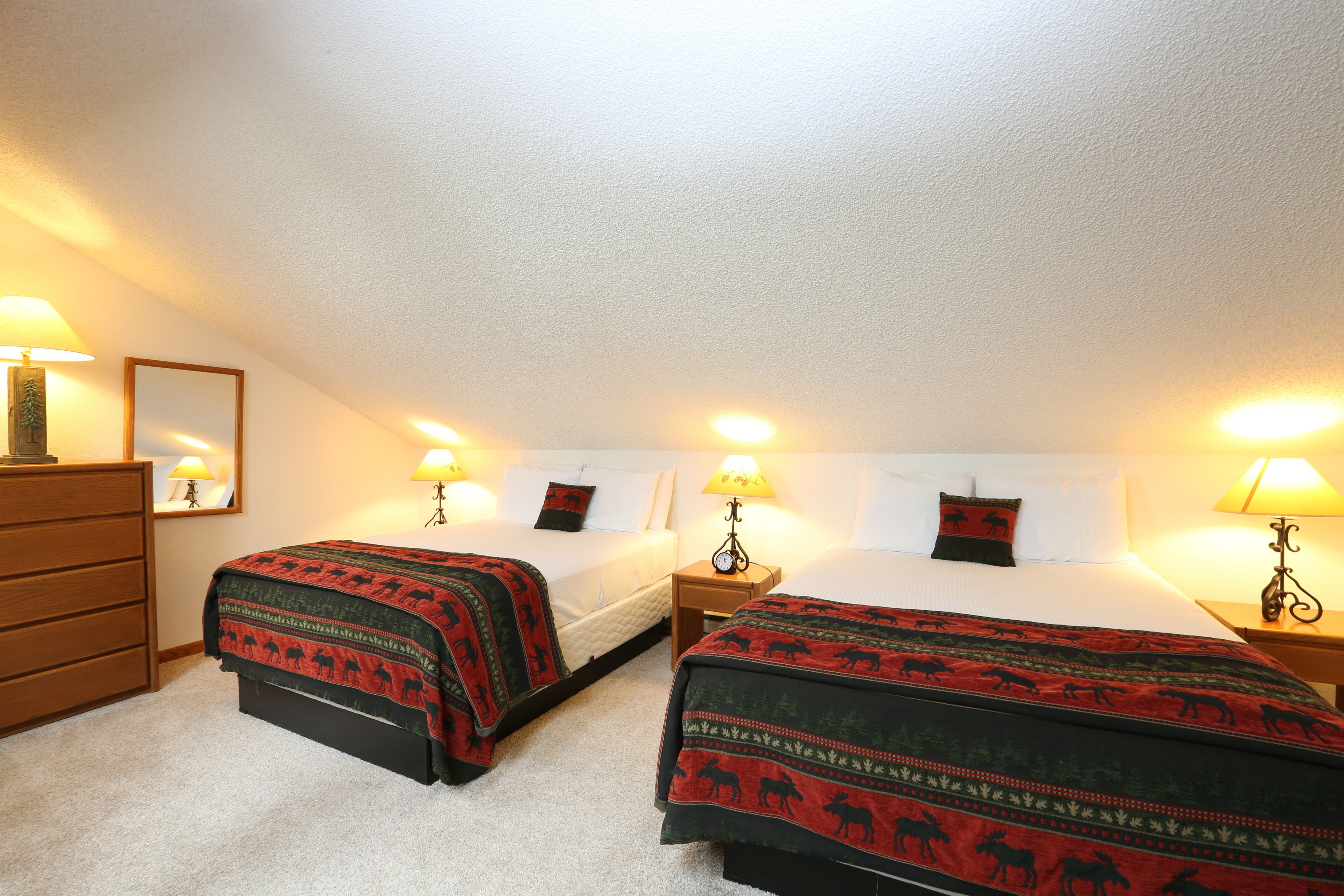 A hotel room with two beds, a dresser, and lamps.