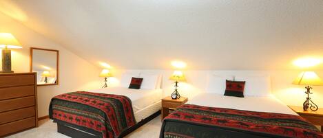 A hotel room with two beds, a dresser, and lamps.
