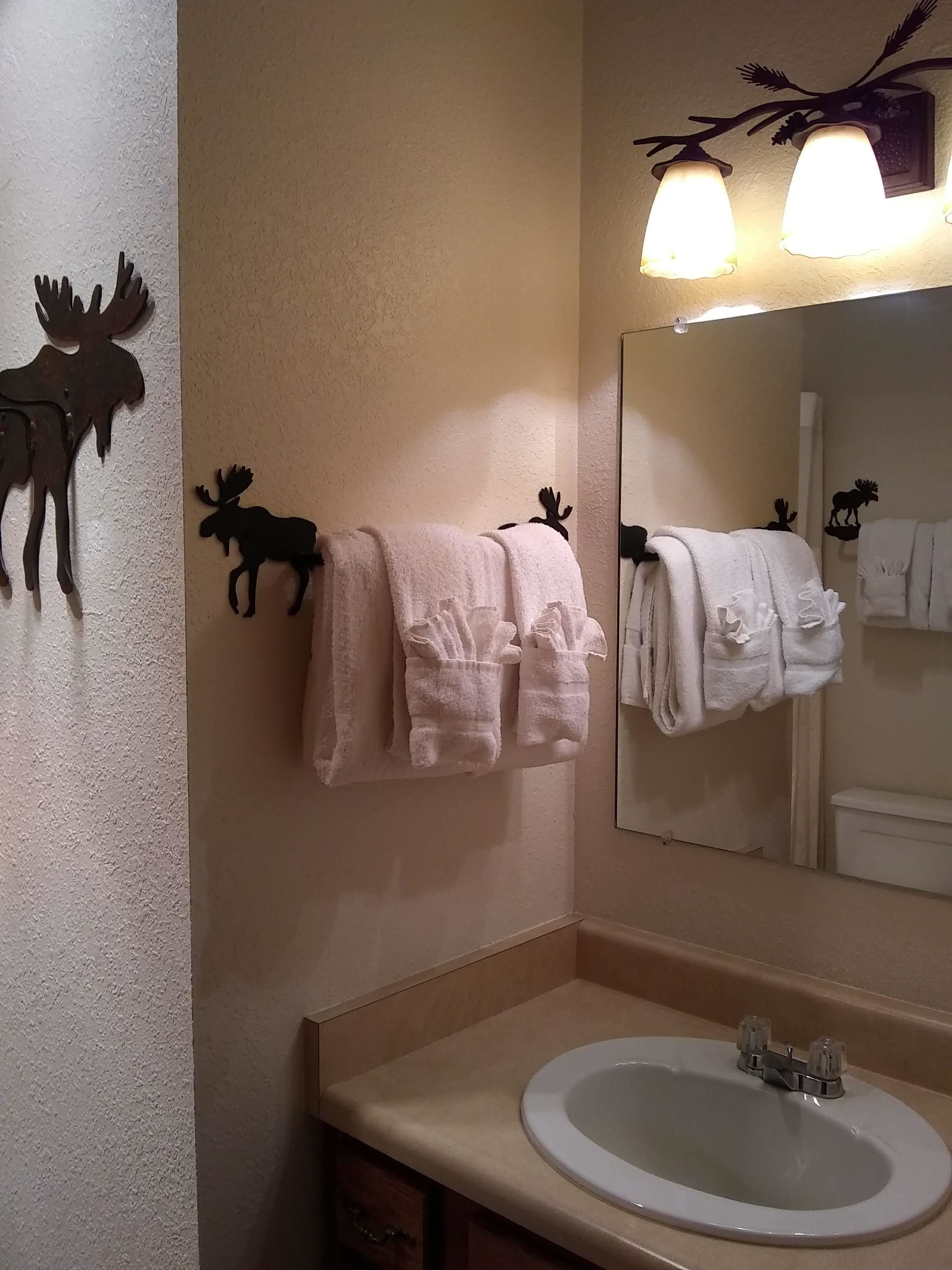 A bathroom with a sink, two moose wall decor, and towels hanging on a rack.