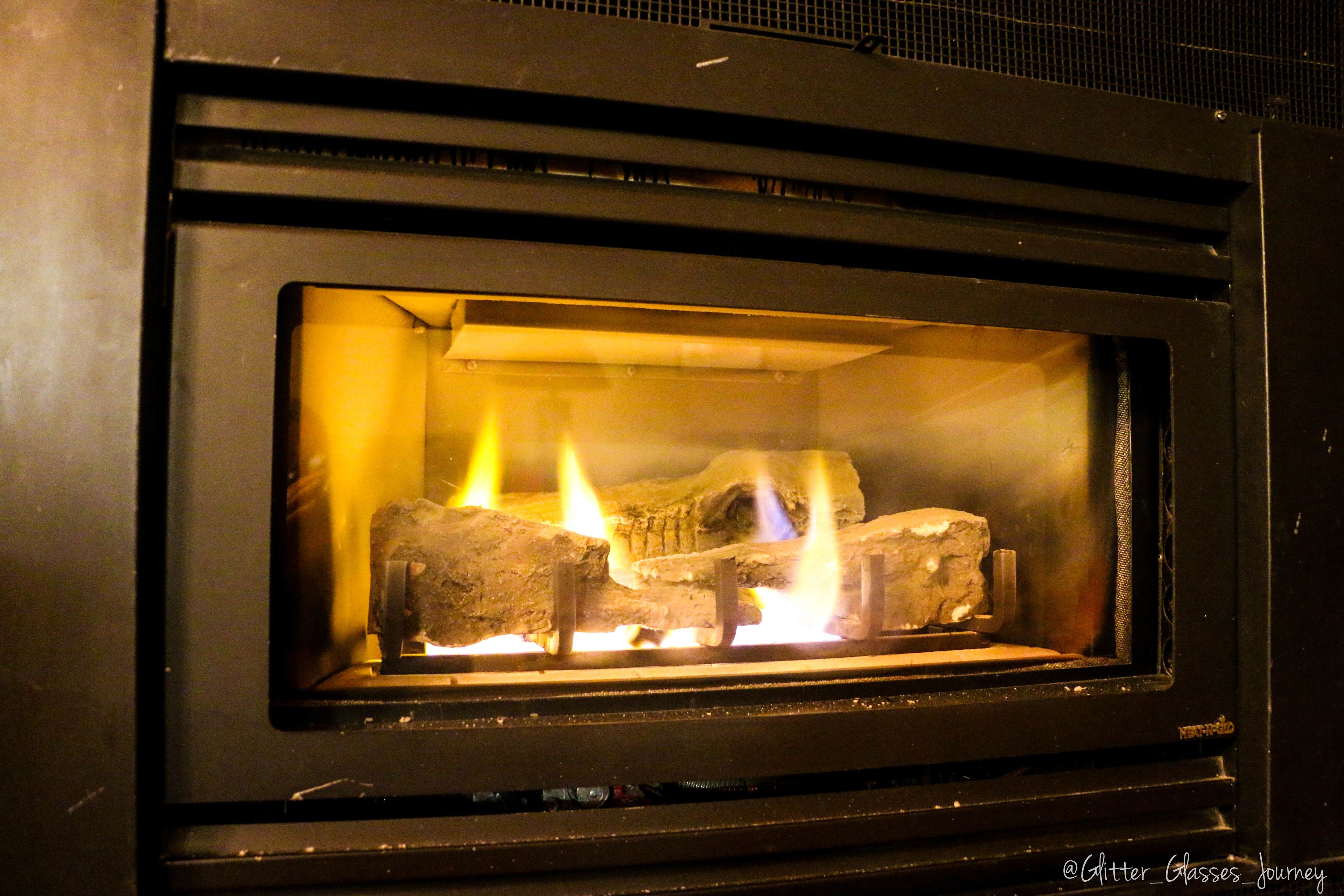A wood-burning stove with visible flames and logs inside.