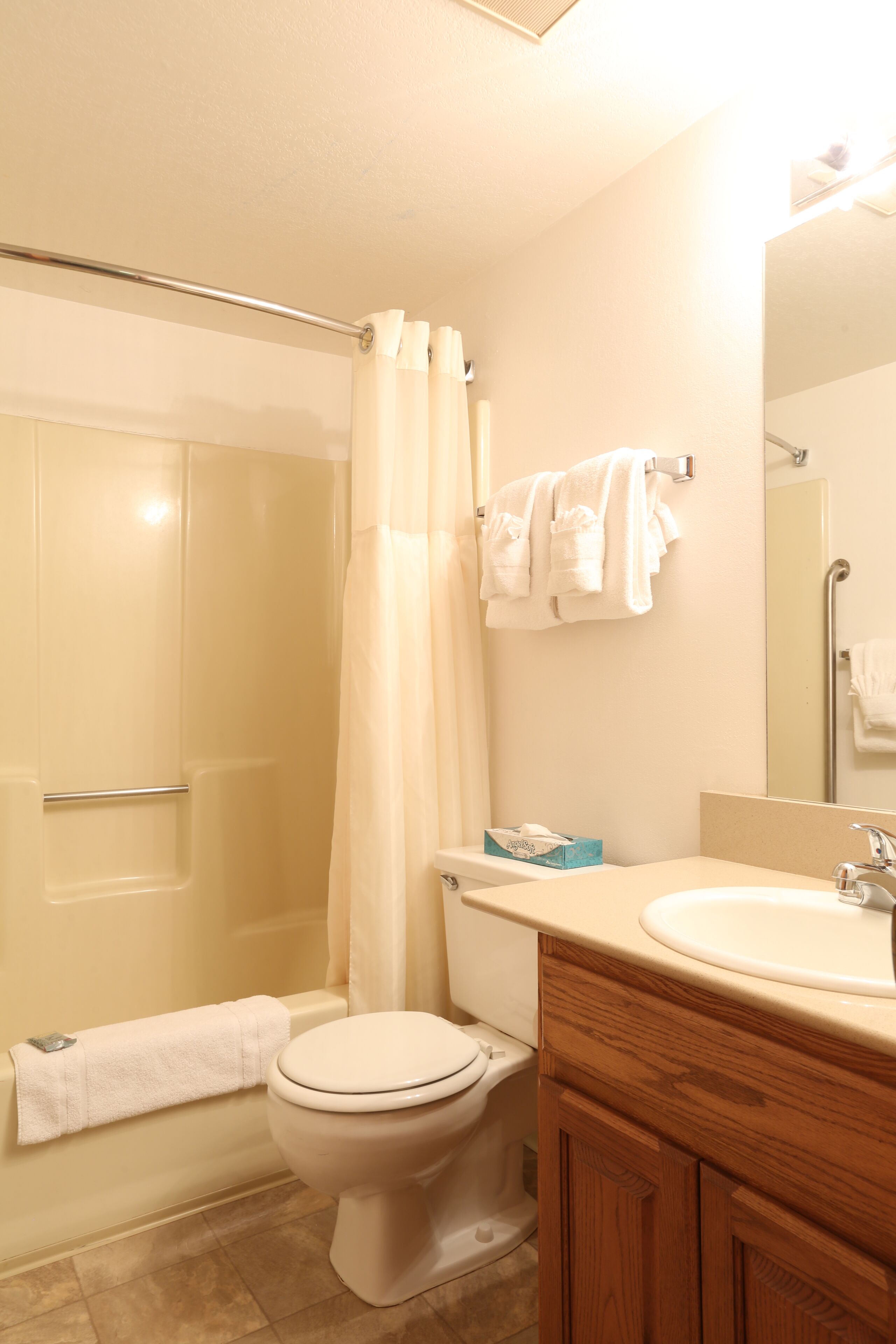 A bathroom with a shower, toilet, sink, and mirror.