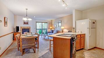 A spacious kitchen with a central island, wooden cabinets, and a built-in oven. There is a dining area with a table and chairs, and a cozy seating area with a sofa and chairs.