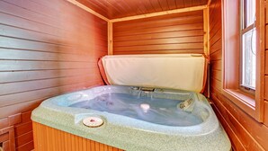 A wooden sauna with a stone hot tub, a control panel, and a window.