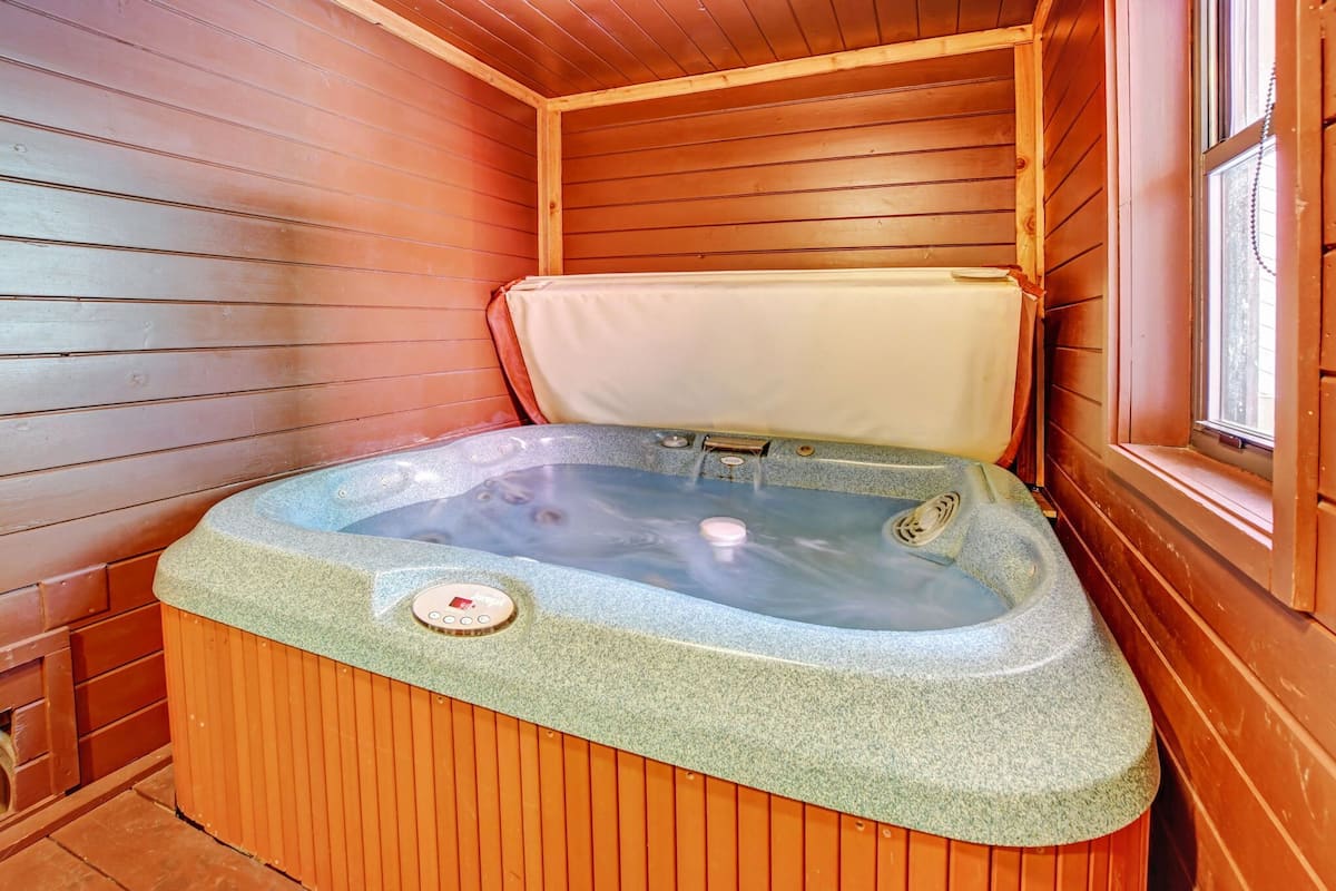 A wooden sauna with a stone hot tub, a control panel, and a window.