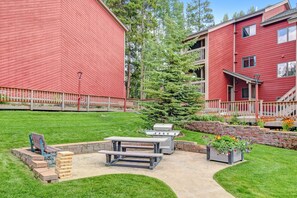 Un bâtiment rouge doté d’un patio comprenant un barbecue, une table de pique-nique et des sièges.
