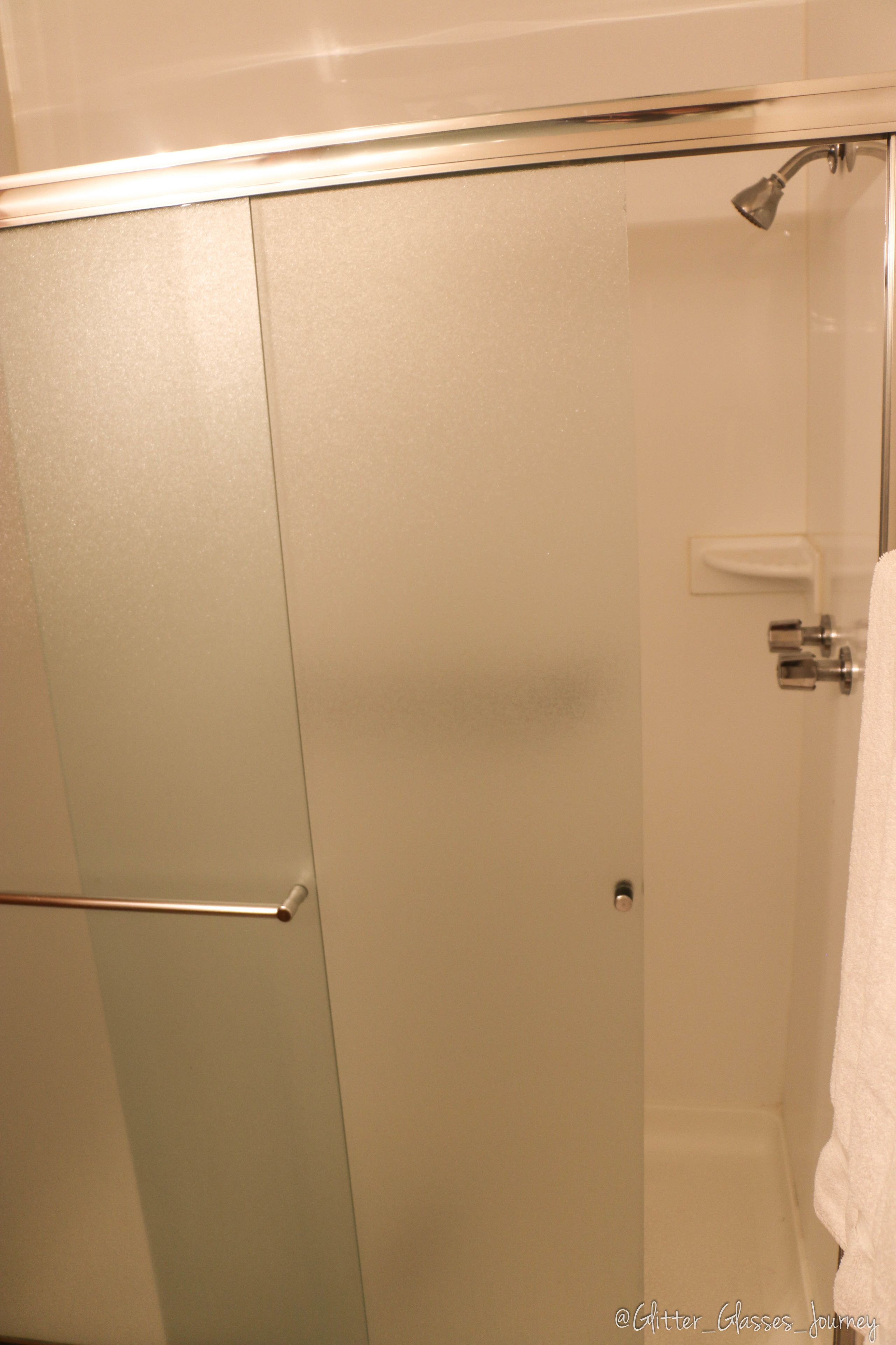 Une salle de bain avec une douche à parois de verre, un porte-serviettes et un support à papier toilette.