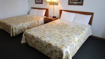 Two single beds with floral bedspreads, a nightstand with a lamp, and two framed pictures on the wall.