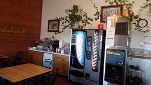 Une cuisine avec des meubles de rangement en bois, un réfrigérateur, une machine à café et une horloge au mur.