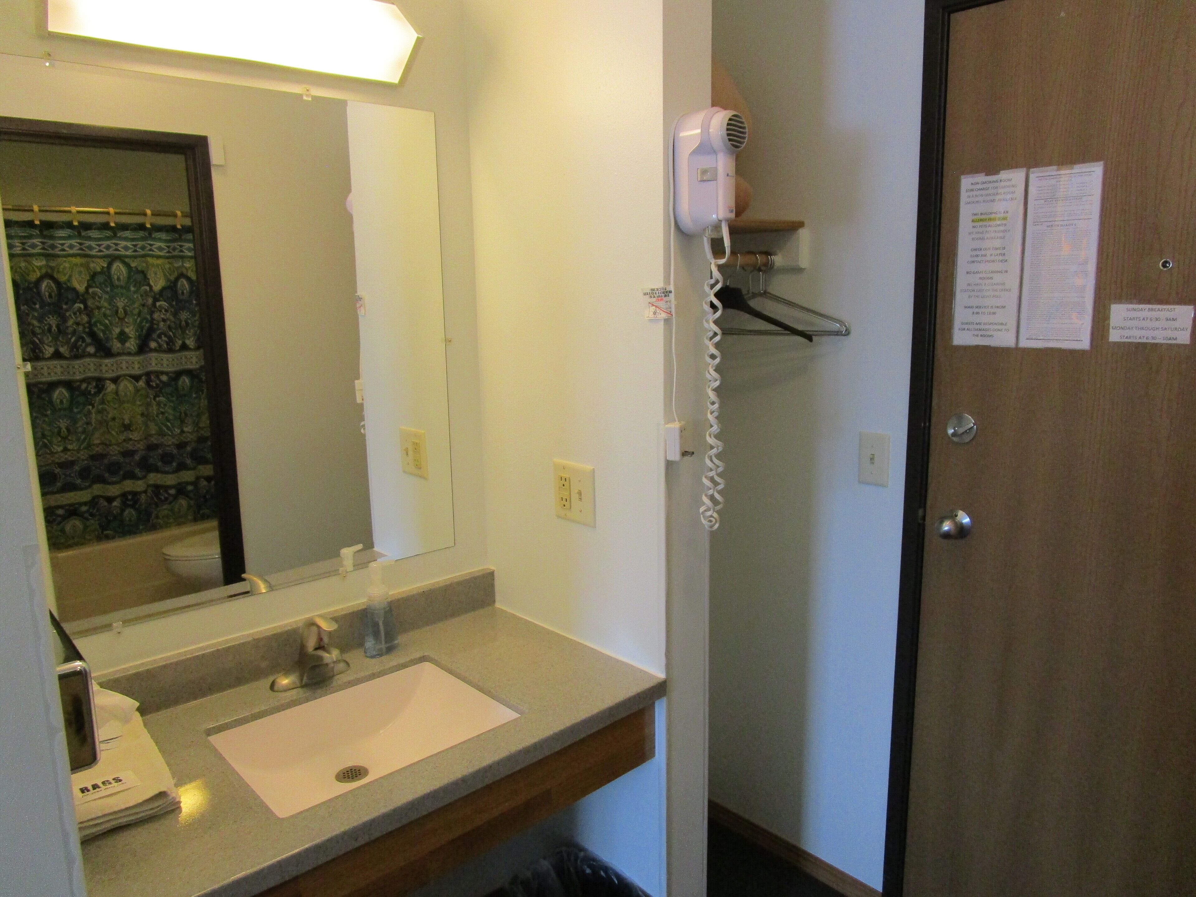 A bathroom with a sink, mirror, and a hairdryer mounted on the wall.