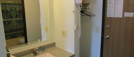 A bathroom with a sink, mirror, and a hairdryer mounted on the wall.