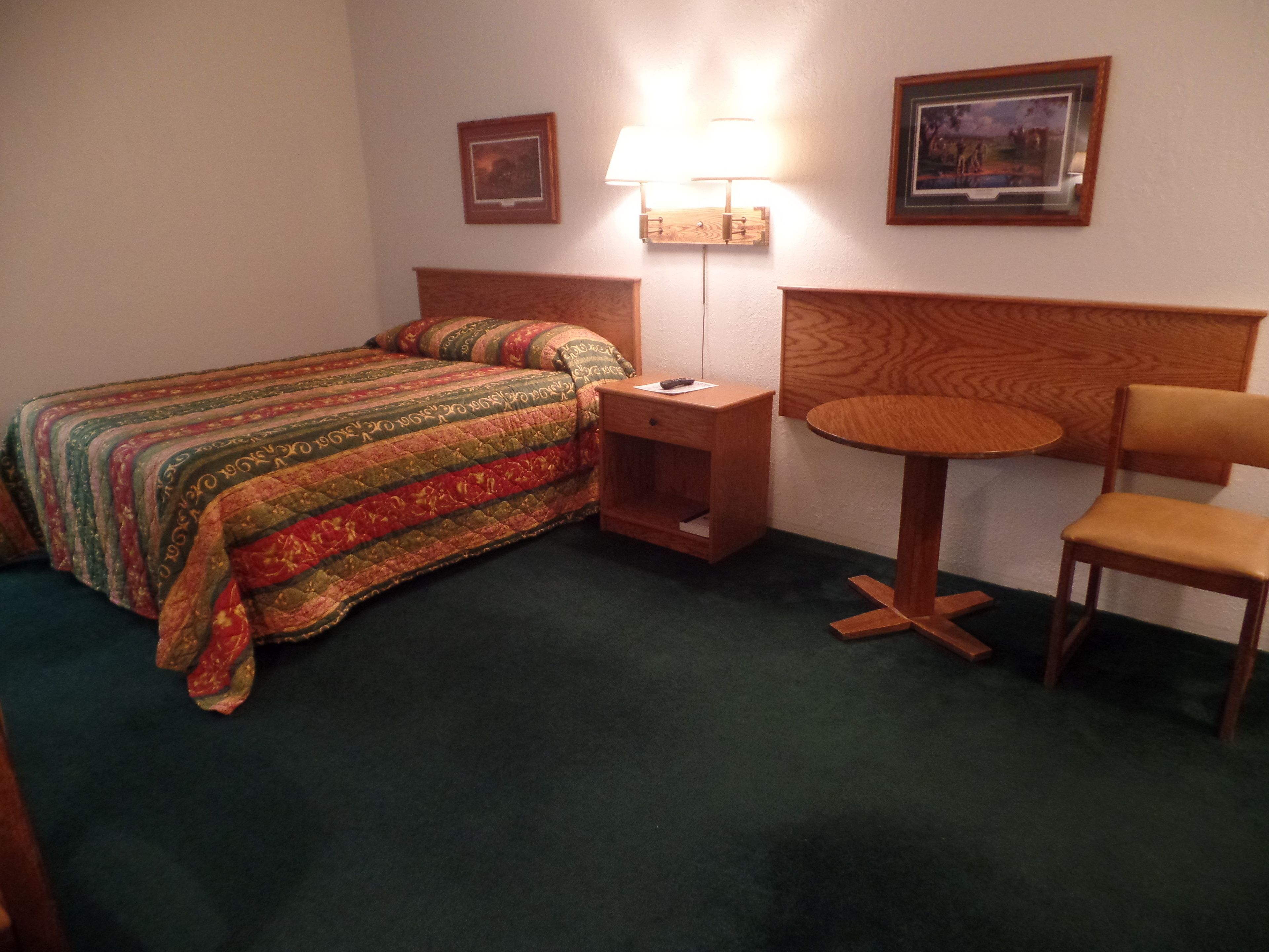 Ein Hotelzimmer mit einem Bett, einem Nachttisch, einem Sessel und einer Lampe.