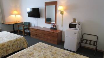 Quarto de hotel com duas camas, uma escrivaninha, televisão, cômoda, micro-ondas e duas luminárias.