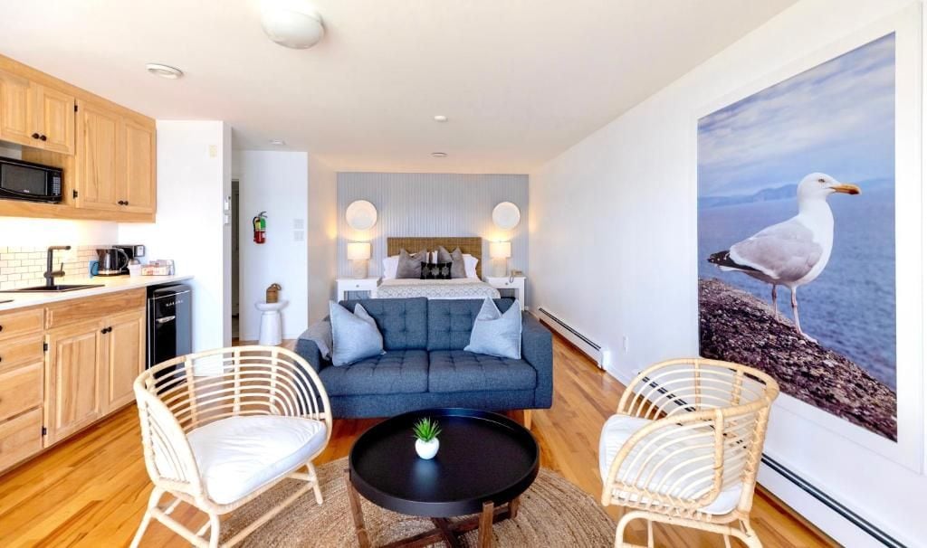 A modern living room with a sofa, two chairs, a coffee table, and a painting of a seagull.