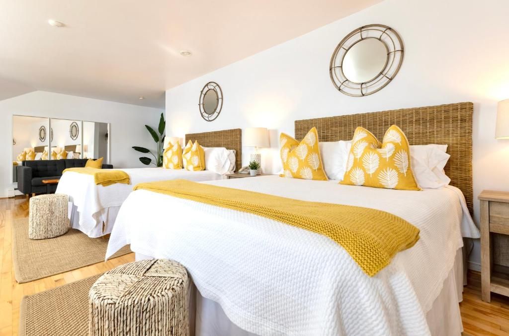 Een hotelkamer met een groot bed, twee nachtkastjes, een spiegel en een wandlamp.