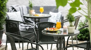 A patio area with outdoor furniture, including round tables and chairs, and a potted plant. - Platinia Apartments (Kraków)
