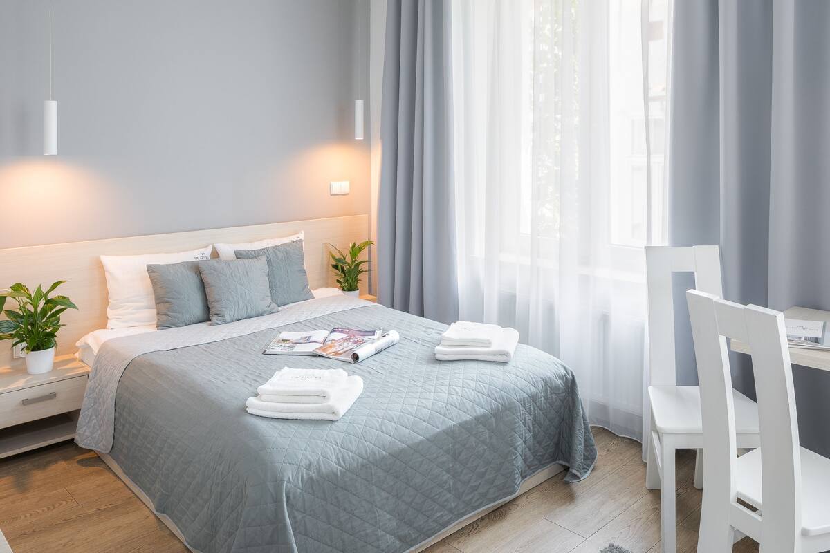 A modern hotel room with a neatly made bed, a small table with breakfast items, and a chair.
