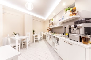 A modern kitchen with white cabinetry, a coffee machine, and a fruit basket on the counter. - Platinia Apartments (Kraków)