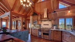 A spacious kitchen with wooden cabinets, a large island, and a central stove. - Glacier Luxury Lodge (Truckee)